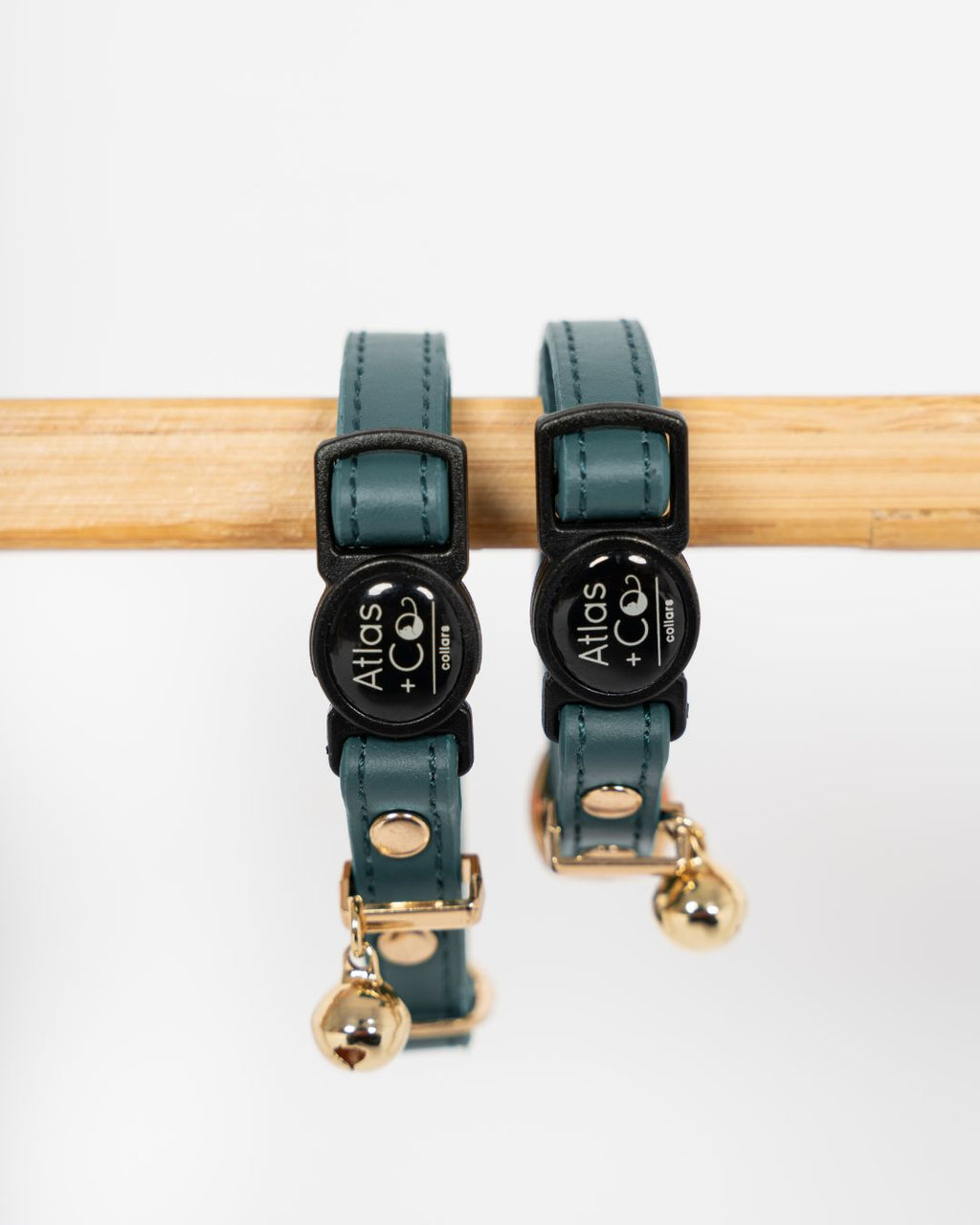 Two teal cat collars with black clasps and gold tags on a white background #colour_Atlas