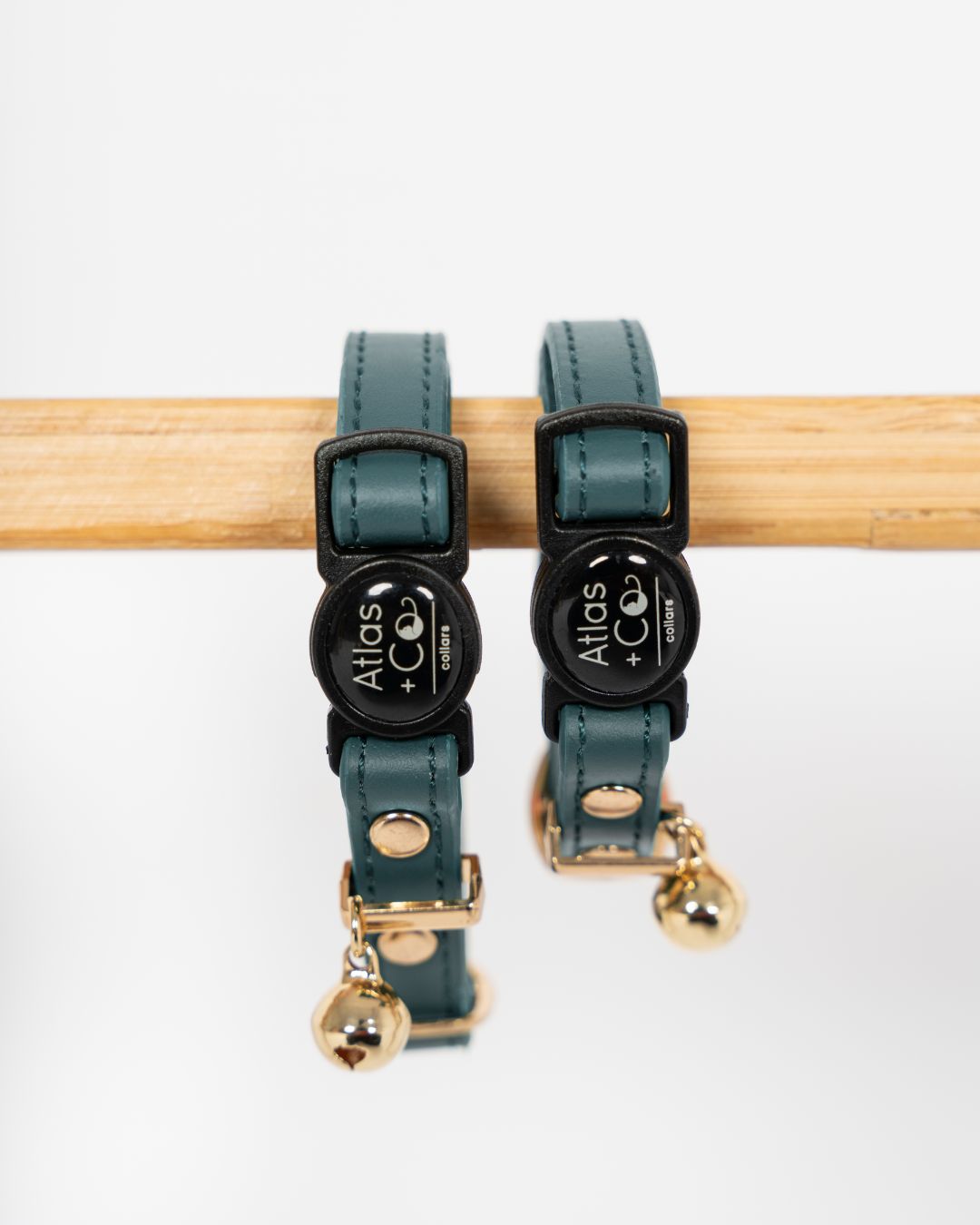 Two teal cat collars with black clasps and gold tags on a white background #colour_Atlas